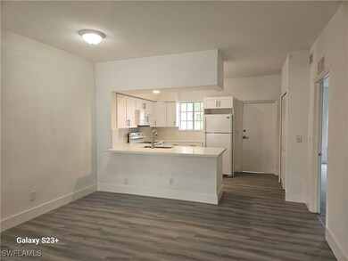 Kitchen featuring dark hardwood / wood-style flooring, white cabinets, kitchen peninsula, and white appliances