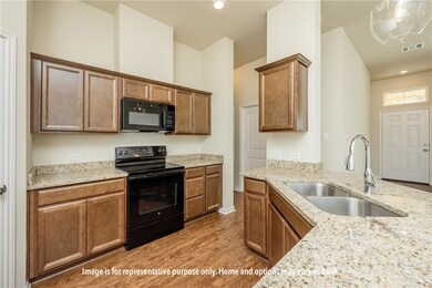 Kitchen with light wood-style flooring, black appliances, light stone counters, recessed lighting, and brown cabinetry