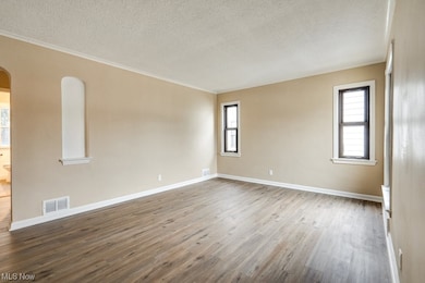 Empty room with crown molding, a textured ceiling, and dark hardwood / wood-style floors