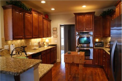 Spacious kitchen features granite countertops, gas cooktop, double ovens, maple cabinets and a breakfast bar.