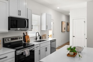 Photos of similar, smaller home. Stunning kitchen with white, quartz countertops, white cabinetry and black accent handles, electric and plumbing fixtures!