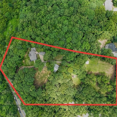 Aerial view of property and surrounding area with property parcel outlined and a heavily wooded area