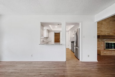Kitchen with light wood-style flooring, white cabinets, appliances with stainless steel finishes, a raised ceiling, and a fireplace