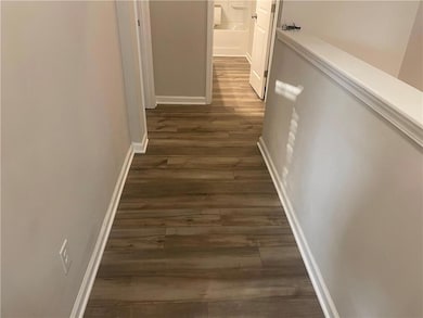 Corridor featuring dark wood finished floors and baseboards