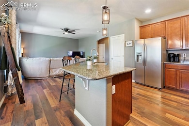 Kitchen with stainless steel fridge, arched walkways, brown cabinetry, a kitchen breakfast bar, and recessed lighting