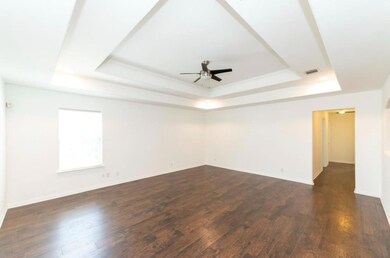 Empty room featuring a tray ceiling, a ceiling fa