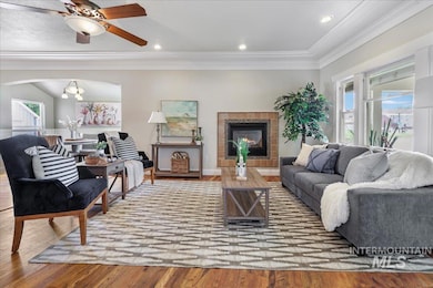 Living area with ornamental molding, wood finished floors, a fireplace, and ceiling fan