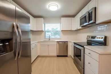 Kitchen featuring appliances with stainless steel finishes, light countertops, and white cabinetry
