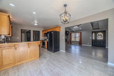 Kitchen featuring black appliances, recessed lighting, a peninsula, hanging light fixtures, and wood finish floors