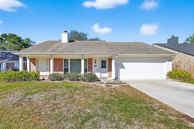 Charming single-story home boasting classic brick accents, a spacious two-car garage, and well-maintained landscaping under a bright blue sky.