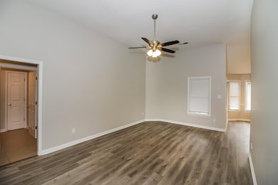 Spare room featuring baseboards, dark wood-style f