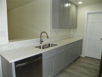 Kitchen with dishwashing machine, gray cabinetry,