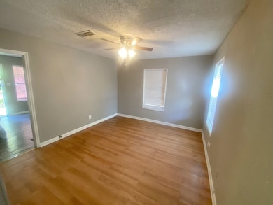 Empty room with wood finished floors, a ceiling fan, and a textured ceiling