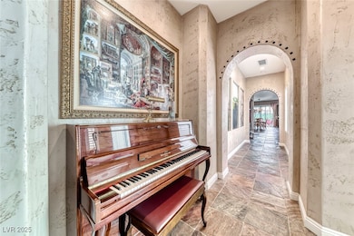 Hallway with visible vents, baseboards, arched wal