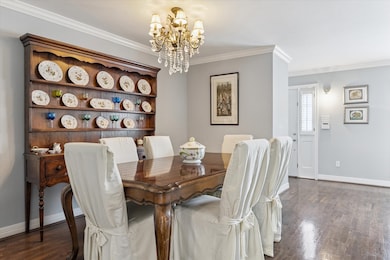 The spacious dining room is accented with a lovely chandelier, hardwood flooring and open to living area.
