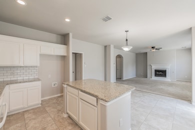 Kitchen with a center island, arched walkways, a ceiling fan, light stone countertops, and tasteful backsplash