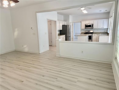 Kitchen featuring appliances with stainless steel finishes, ceiling fan, light wood finished floors, white cabinetry, and light countertops