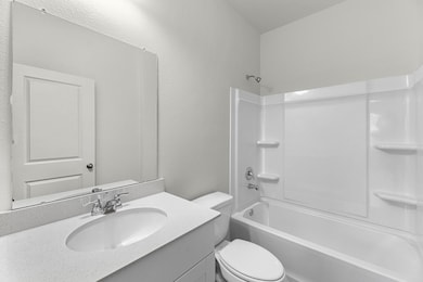 Bathroom with a textured wall, vanity, and bathing tub / shower combination