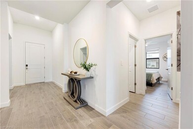 Hallway with light wood-type flooring, visible ven