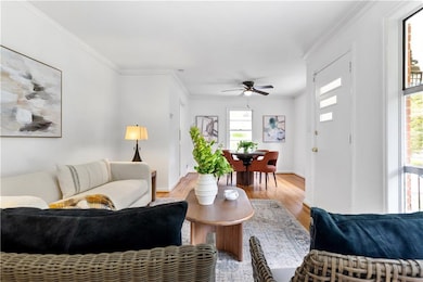 Living room with light wood-style flooring, ornamental molding, baseboards, and ceiling fan