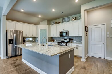 ALTERNATE VIEW OF KITCHEN  Island kitchen opens to dining and living areas providing excellent entertaining opportunity.  Door at right leads to the garage.