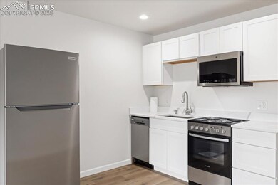 Kitchen with stainless steel appliances, light wood-type flooring, light countertops, white cabinetry, and recessed lighting