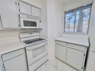 Kitchen featuring marble finish floor, white appliances, and light countertops