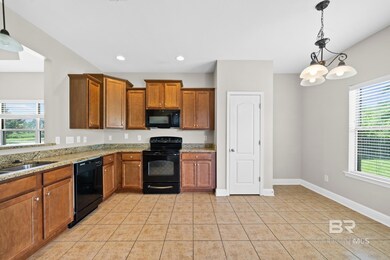 Kitchen featuring a wealth of natural light, black appliances, decorative light fixtures, and light tile patterned floors