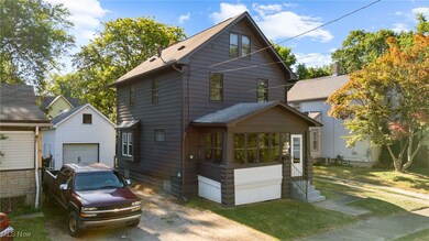 View of front of property featuring a garage, entry steps, an outbuilding, roof with shingles, and driveway