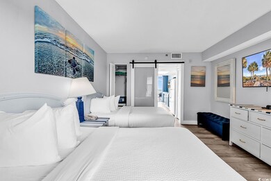 Bedroom featuring baseboards, a barn door, dark wo