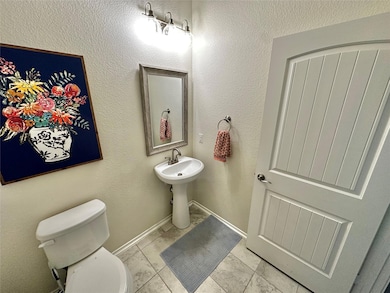 Half bathroom featuring a textured wall and baseboards