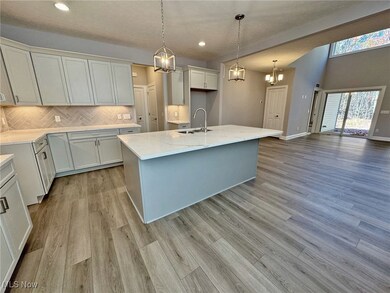 Kitchen featuring quartz counters, decorative backsplash, 2 pendants, an island with sink, and recessed lighting & eat in dinette