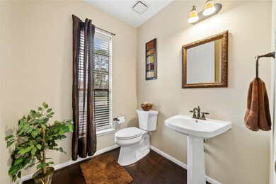 The powder bathroom is fitted with oil rubbed bronze fixtures, a pedestal sink, and framed mirror.