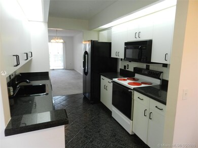 Galley kitchen with white cabinetry and granite counters