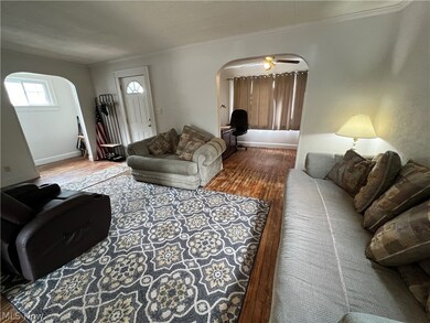 Living room with crown molding, wood-type flooring, and ceiling fan