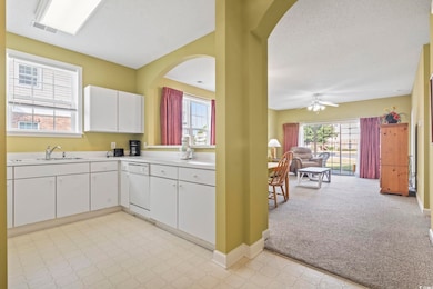 Kitchen with light countertops, white cabinetry, a textured ceiling, light carpet, and open floor plan