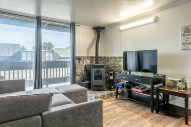 Living room with a wood stove, wood finished floors, and ornamental molding