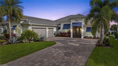 View of front facade featuring decorative driveway, a garage, a tiled roof, and a lawn
