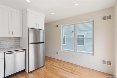 Kitchen with stainless steel appliances, white cabinetry, recessed lighting, light wood finished floors, and light stone counters