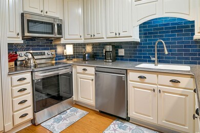 Kitchen with stainless steel appliances, a sink, backsplash, and light wood finished floors