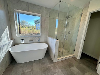 Bathroom featuring a soaking tub, a shower stall,