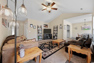 Carpeted living area with ceiling fan and vaulted ceiling