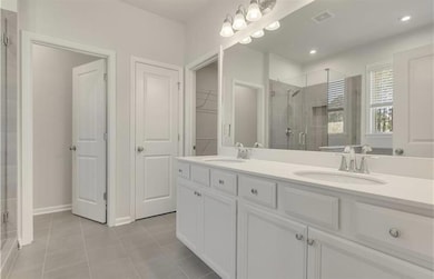 Full bathroom featuring a stall shower, tile patterned flooring, double vanity, a walk in closet, and recessed lighting