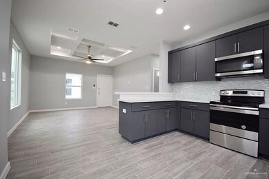 Kitchen with ceiling fan, coffered ceiling, a peninsula, appliances with stainless steel finishes, and visible vents