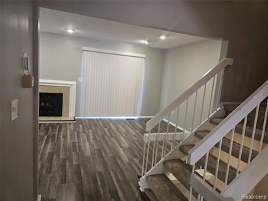 Stairs with wood finished floors and a fireplace with raised hearth