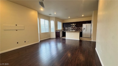 Unfurnished living room with dark wood-style floors, a textured wall, and recessed lighting