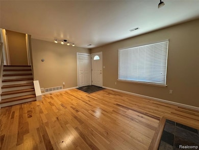 Entryway featuring light wood-style floors, stairs, and rail lighting