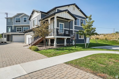 View of front of house with board and batten siding, decorative driveway, a front lawn, covered porch, and stairway