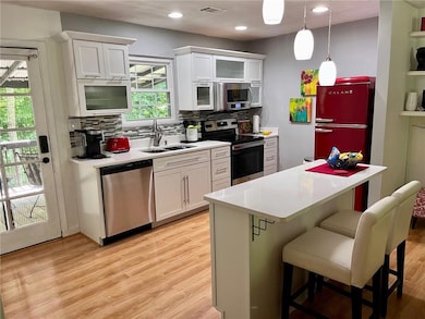 Kitchen featuring a kitchen breakfast bar, light wood-style flooring, a sink, light countertops, and appliances with stainless steel finishes