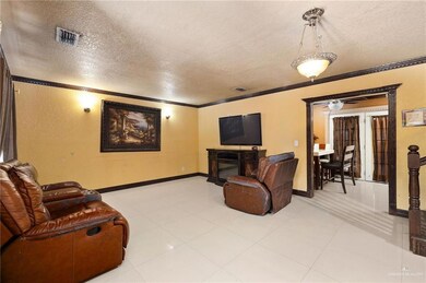 Living area featuring a textured ceiling, crown molding, a glass covered fireplace, a textured wall, and light tile patterned floors